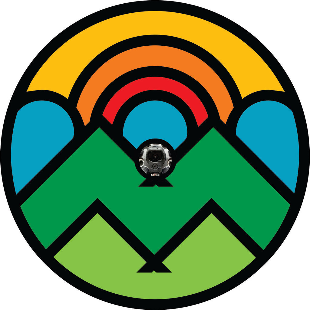 Big shapes and bright bold colors outlined in black make up the illusion of a mountain and sun scene spare tire cover design with a back up camera hole.
