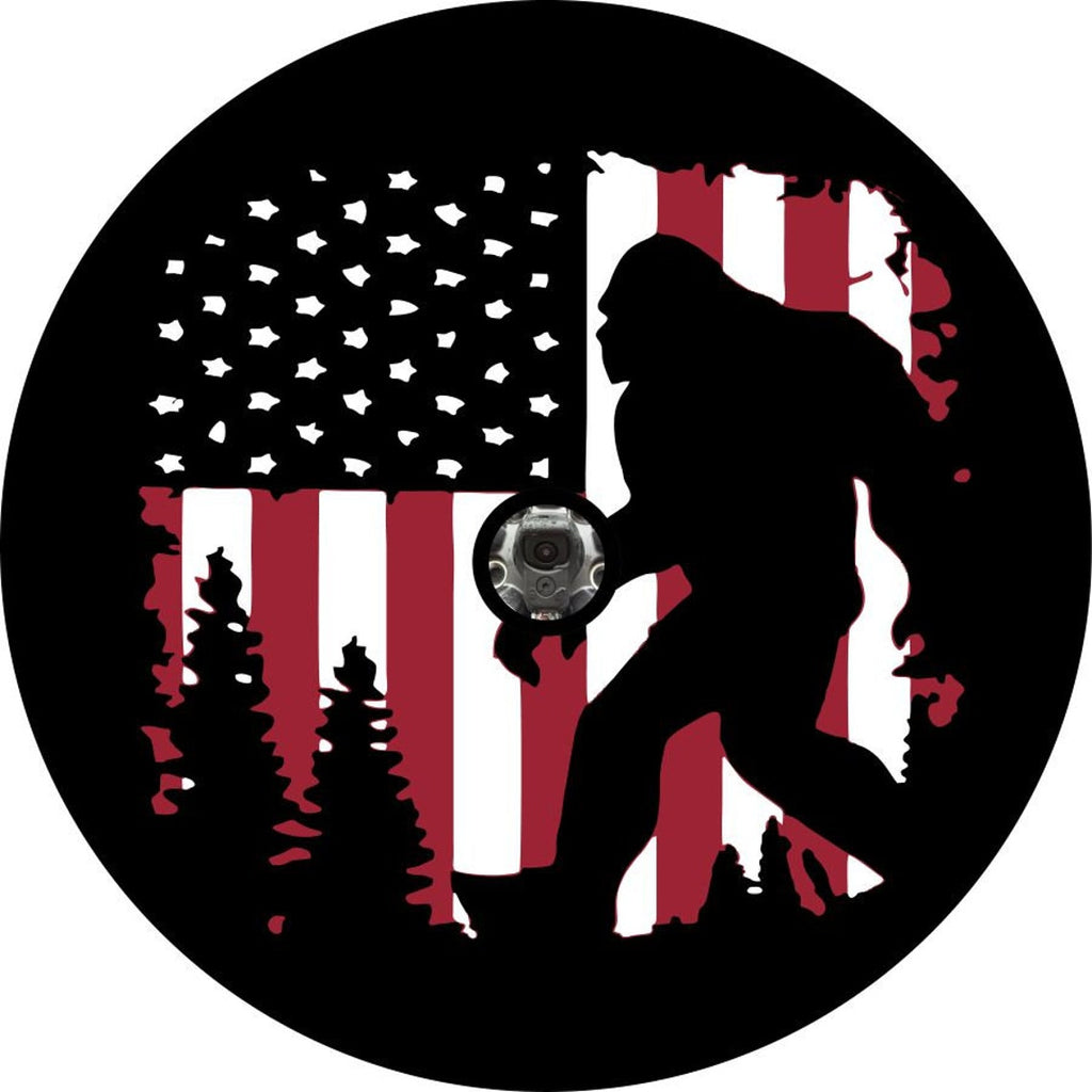 spare tire cover design has Bigfoot walking through the forest with a rustic old glory, the American flag, as the background - create with a back up camera design