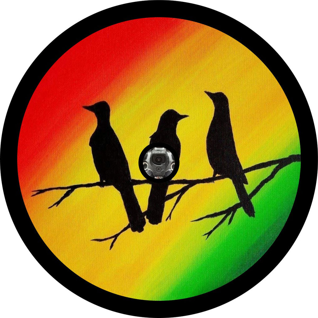 Vinyl spare tire cover for Jeep, Bronco, Campers, and more of red, yellow, and green Rastafarian painted colors and the silhouette of three little birds sitting on a stick. Wheel cover inspired by the Bob Marley song, Three Little Birds. This spare tire cover fits vehicles with backup cameras within their their spare tires.