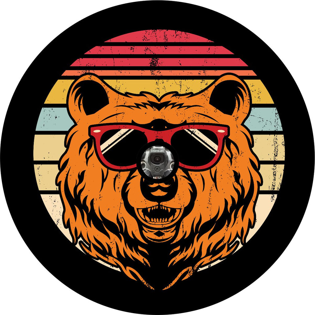 Spare tire cover for back up camera on black vinyl of red, yellow, and cream stripes in the background with a rustic vintage look and a bear head wearing sunglasses.