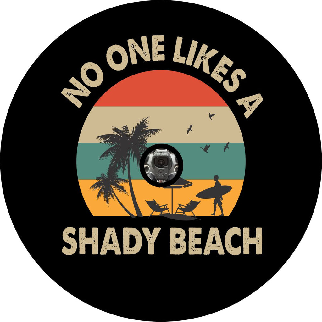 Mock up of a black vinyl spare tire cover with back up camera hole with the image of a beach silhouette, surfer, beach chairs and palm trees. Colors of red, turquoise, and orange. The saying no one likes a shady beach